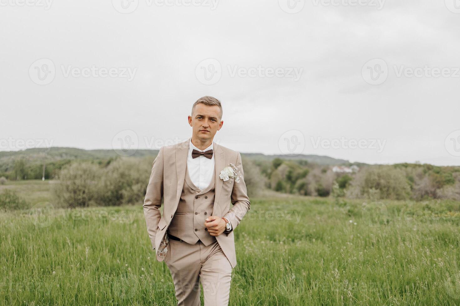 A man in a suit and tie is walking through a field photo
