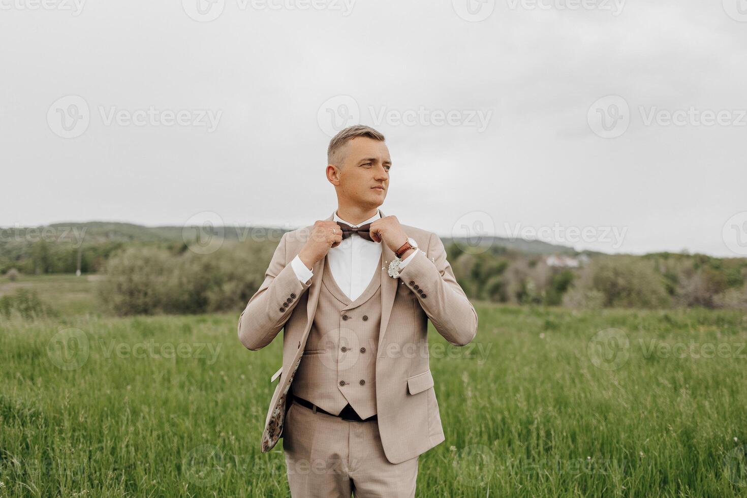 A man in a suit and tie stands in a field photo