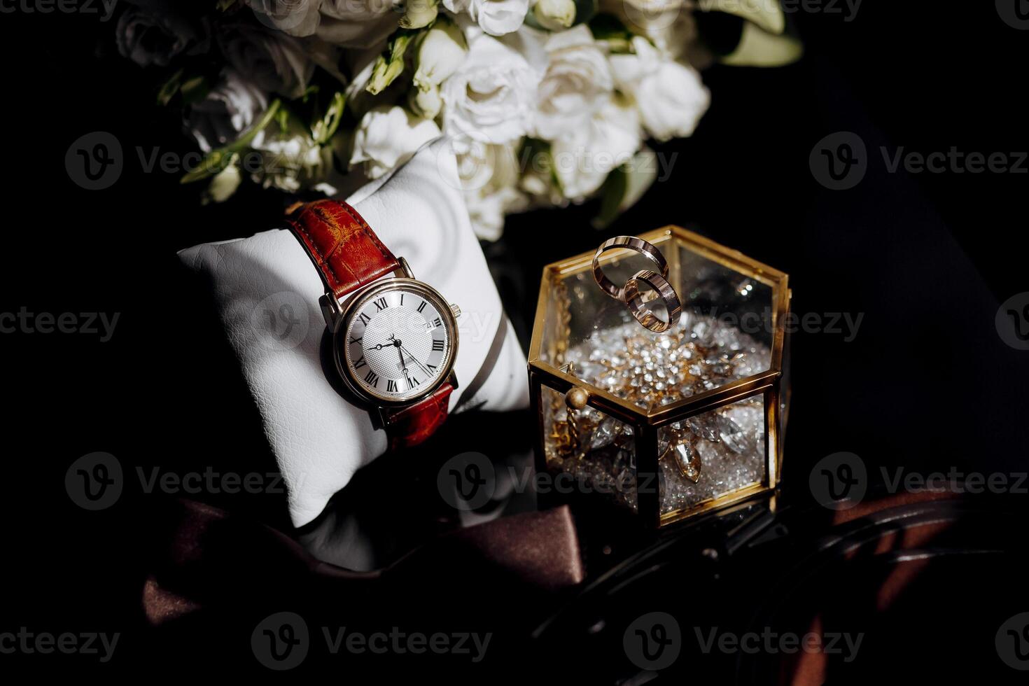 A watch and a ring are displayed on a table photo