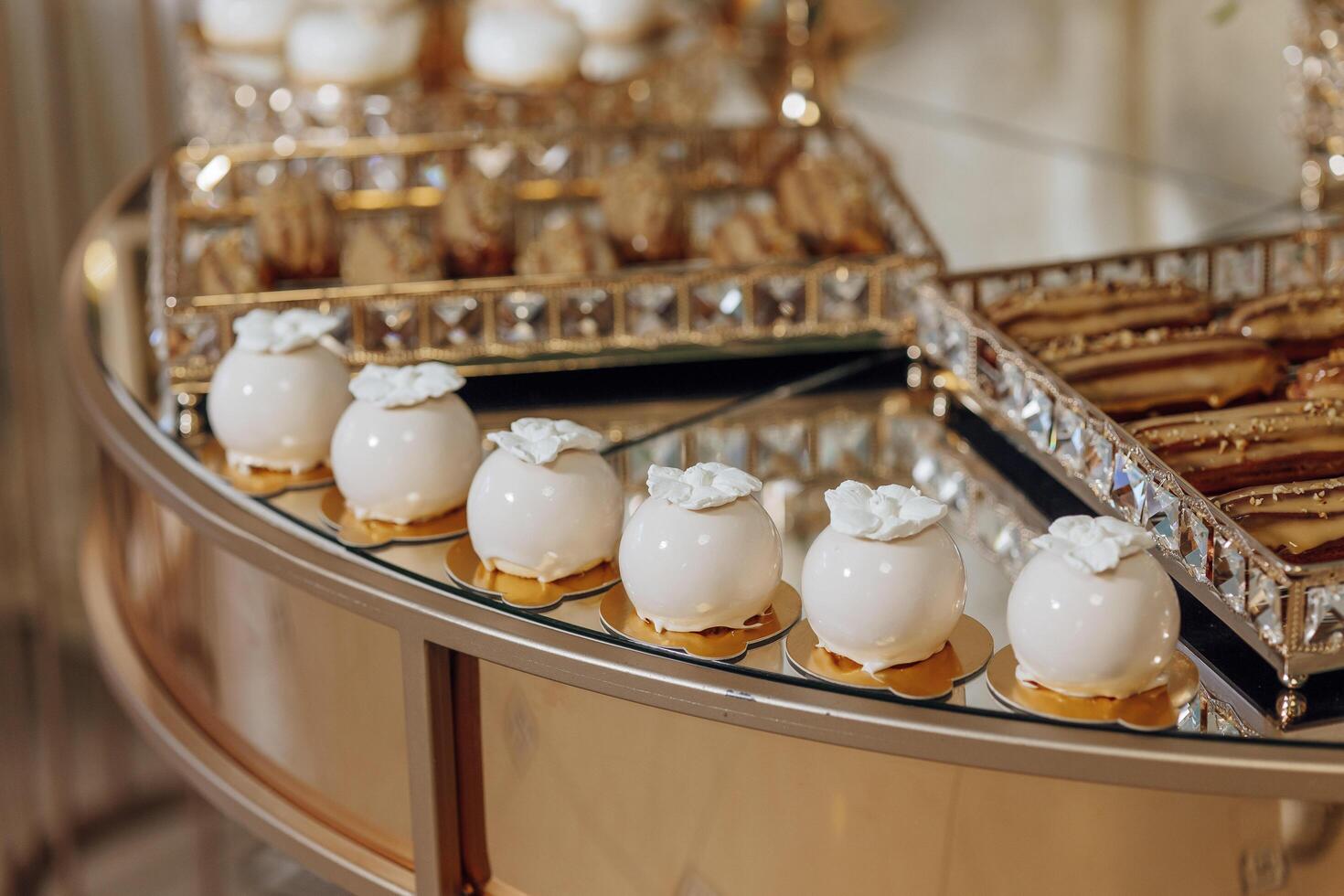 A table with a variety of desserts, including cakes and cookies, arranged in a circular pattern. The desserts are displayed on a gold tray, and there are several different types of cakes and cookies photo