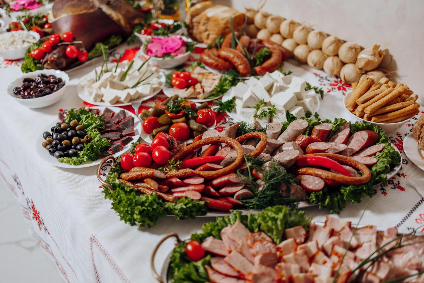 A table is covered with a variety of meats, vegetables, and bread photo