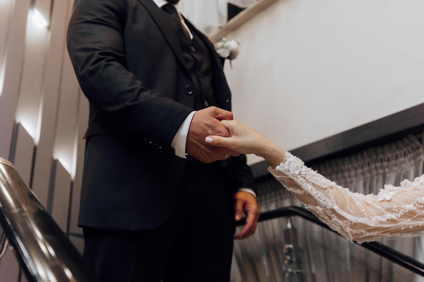 A man and a woman are shaking hands in a black suit and a white dress. The man is wearing a tie and the woman is wearing a wedding dress. Concept of formality and respect as the man photo