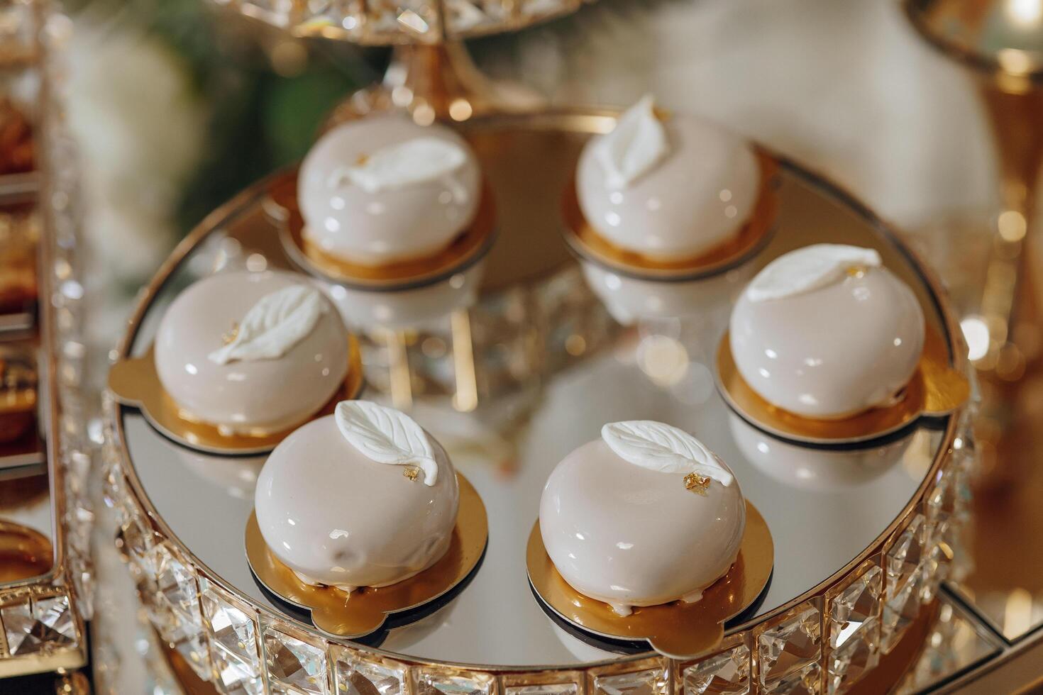 A tray of desserts with a leaf design on top. The desserts are small and arranged in a row photo