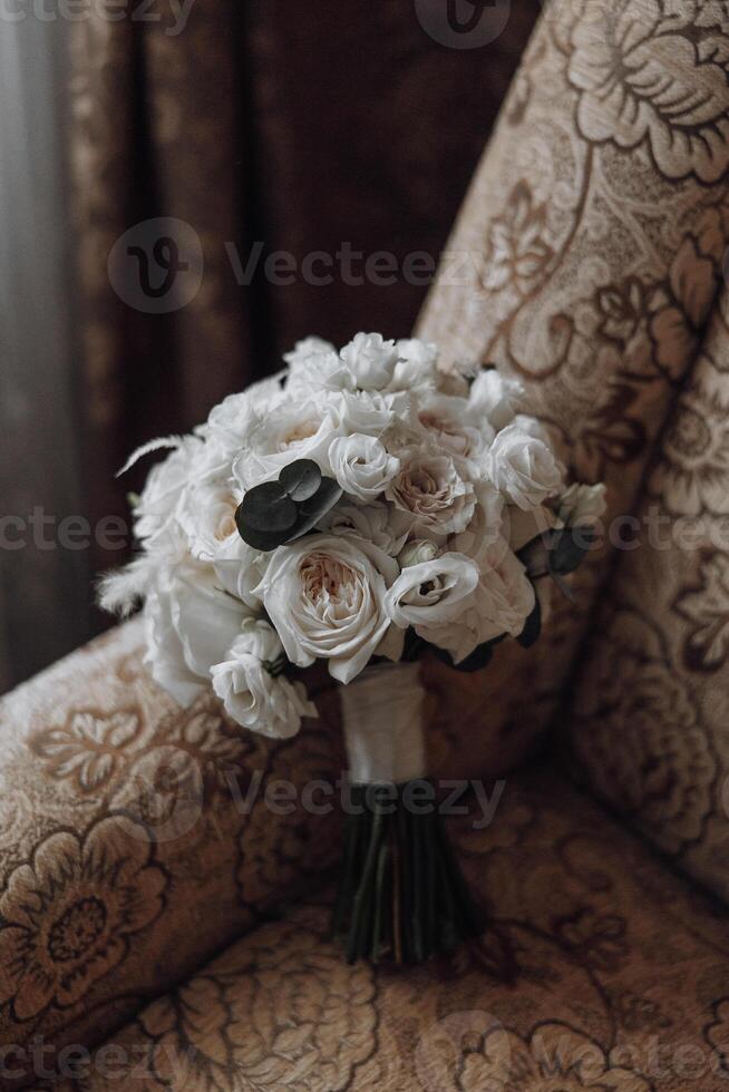 A bouquet of white flowers sits on a chair. The flowers are arranged in a way that they look like they are about to be given as a gift. The chair is covered in a patterned fabric photo