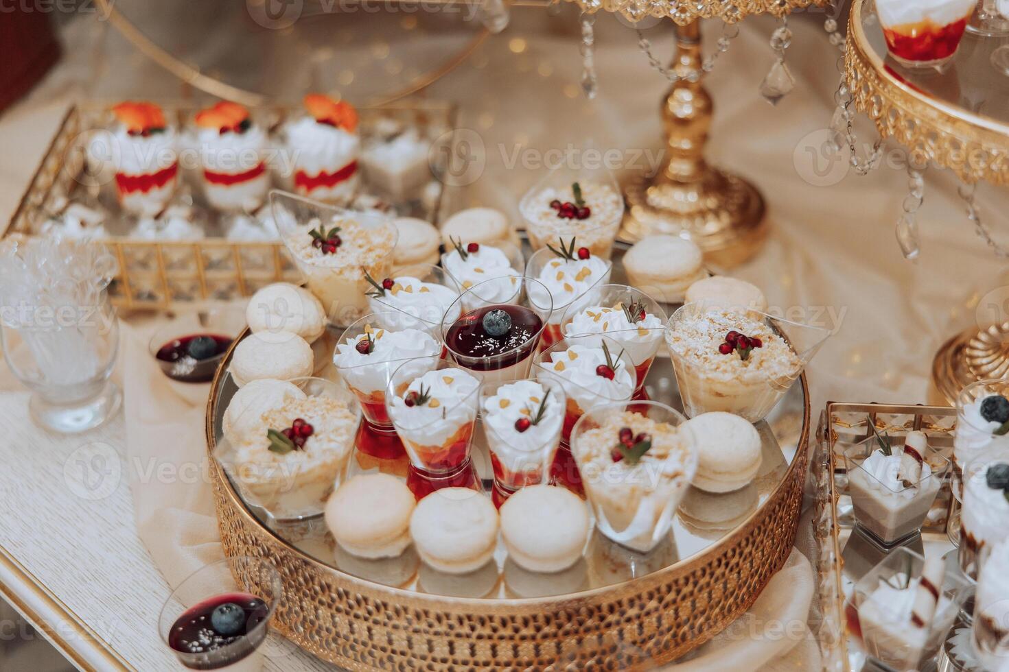 A table with a variety of desserts, including cakes, pastries, and fruit tarts. The desserts are arranged in small, individual serving dishes, and there are also some drinks on the table photo