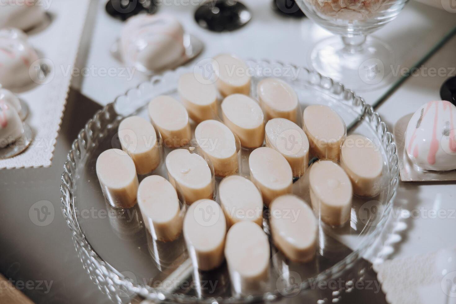 A tray of small, white pastries sits on a table. The pastries are arranged in a neat row, and there are several different types of pastries on the tray. Scene is one of indulgence and enjoyment photo