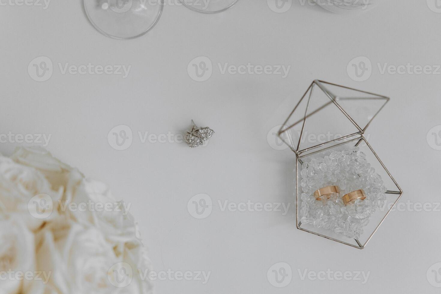 A diamond ring is displayed in a glass case. The ring is surrounded by a bouquet of white flowers photo