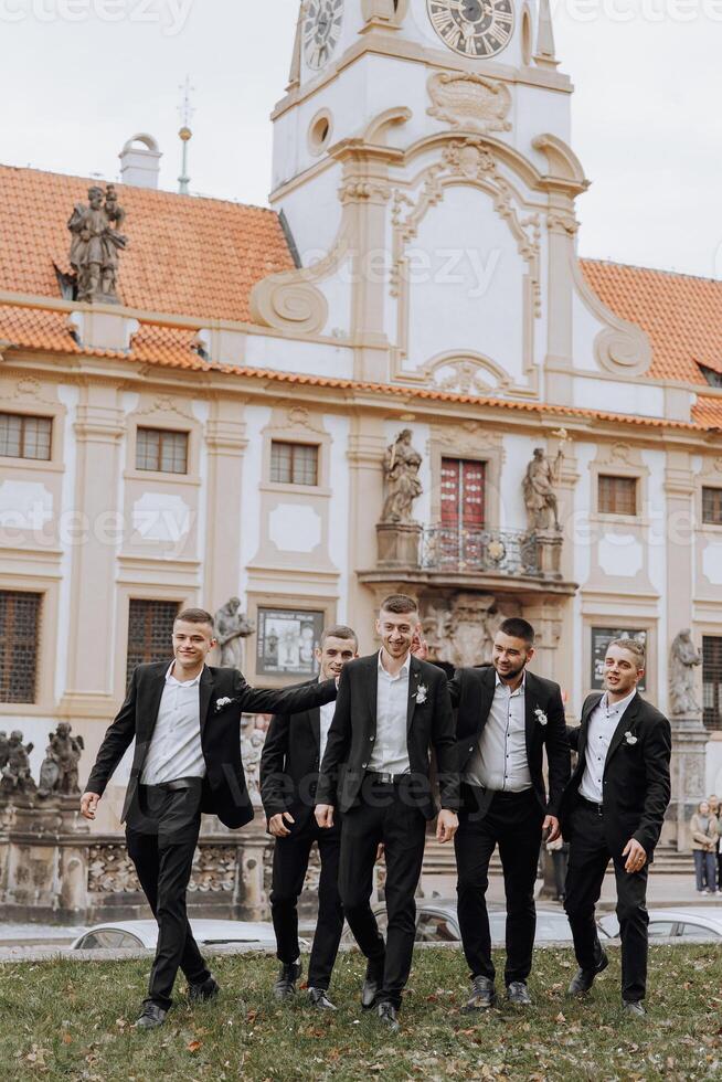 A group of men in suits are walking down a street in front of a large building. Scene is formal and professional, as the men are dressed in suits and ties photo