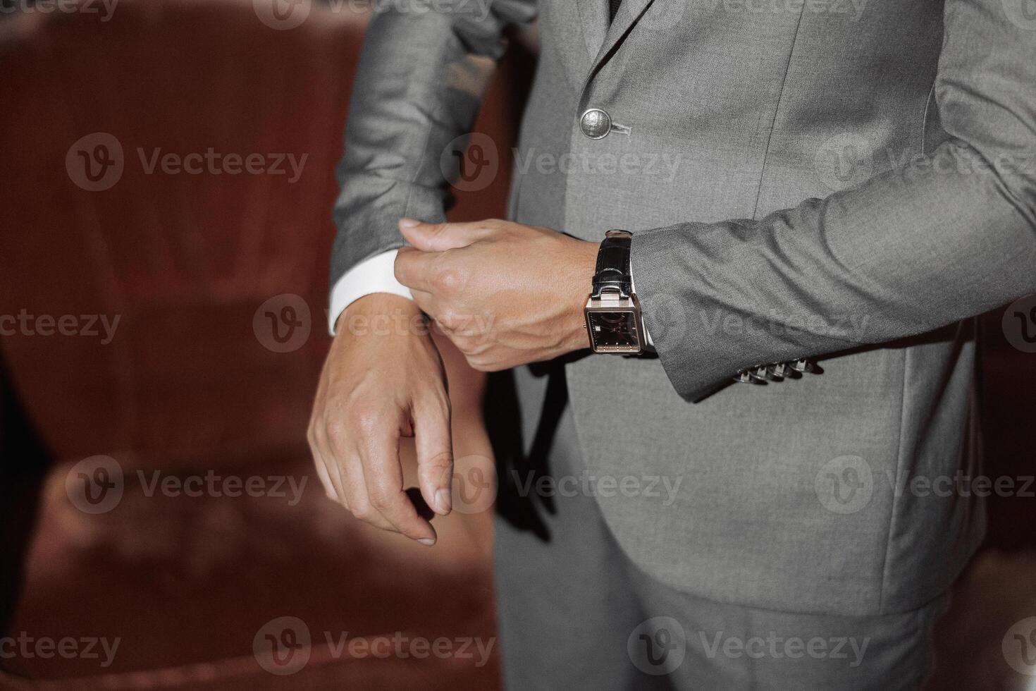 A man in a suit is adjusting his watch. Concept of formality and attention to detail photo