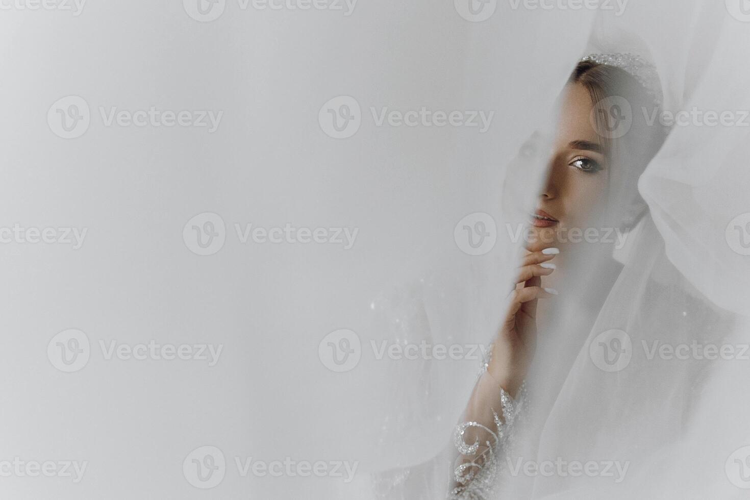 A woman is standing in front of a curtain, looking at the camera. She is wearing a white dress and has her hands on her hips. Concept of mystery and intrigue photo