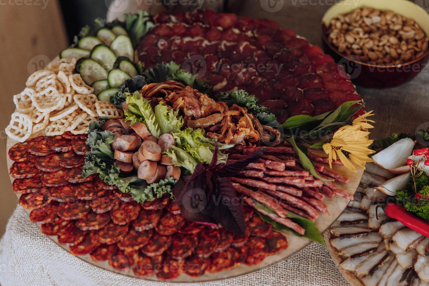 A large platter of assorted meats and vegetables is displayed on a table. The platter is filled with a variety of meats, including sausage, ham, and salami, as well as vegetables such as lettuce photo