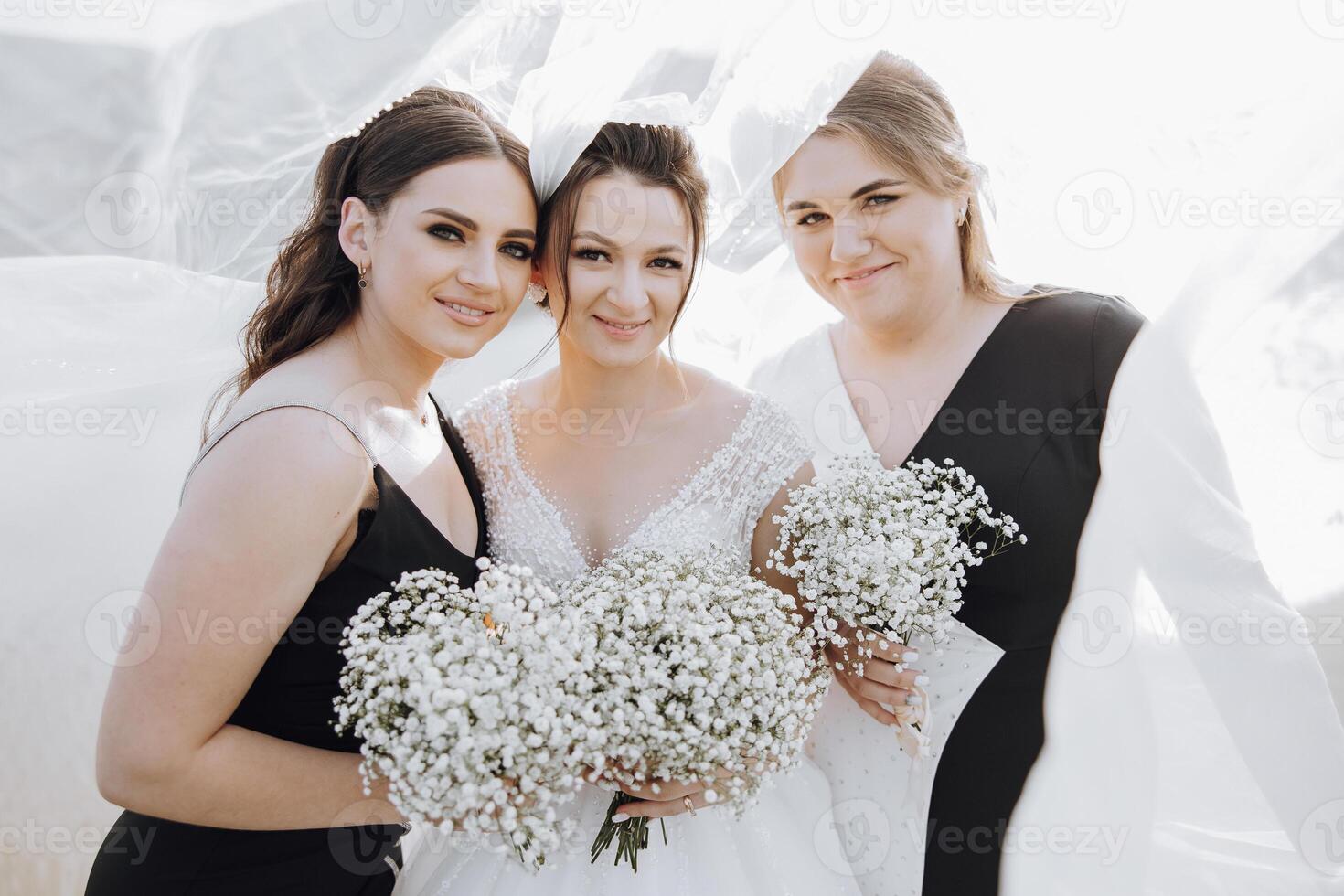 Three women are posing for a photo, each holding a bouquet of white flowers. The women are dressed in black and white, and the scene has a vintage feel to it photo