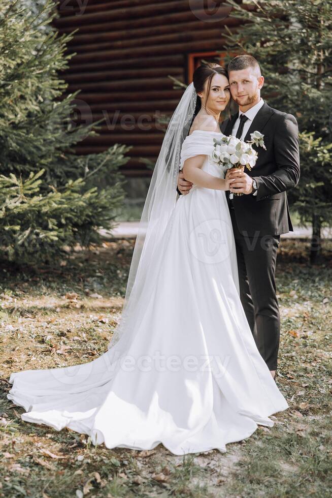 A bride and groom are posing for a picture in front of a log cabin photo