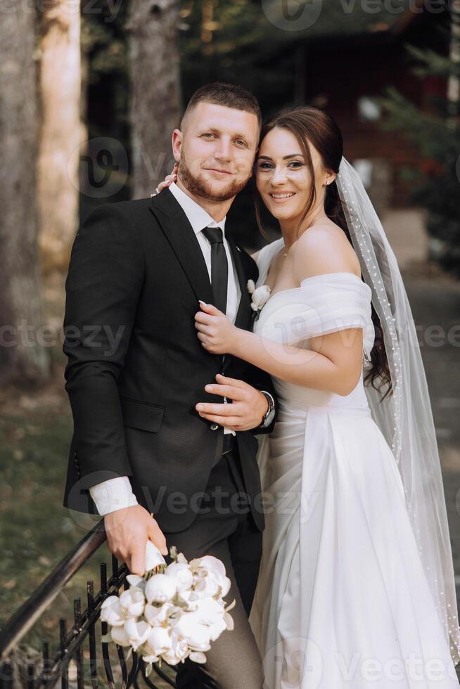 A bride and groom are posing for a picture in front of a fence photo