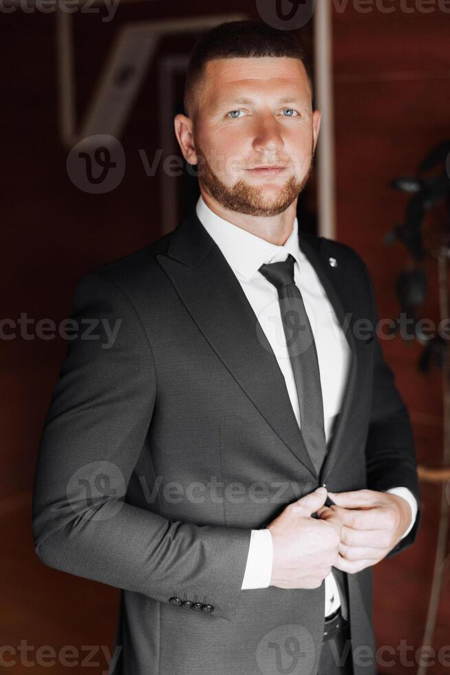 A man in a suit and tie is standing in front of a door photo