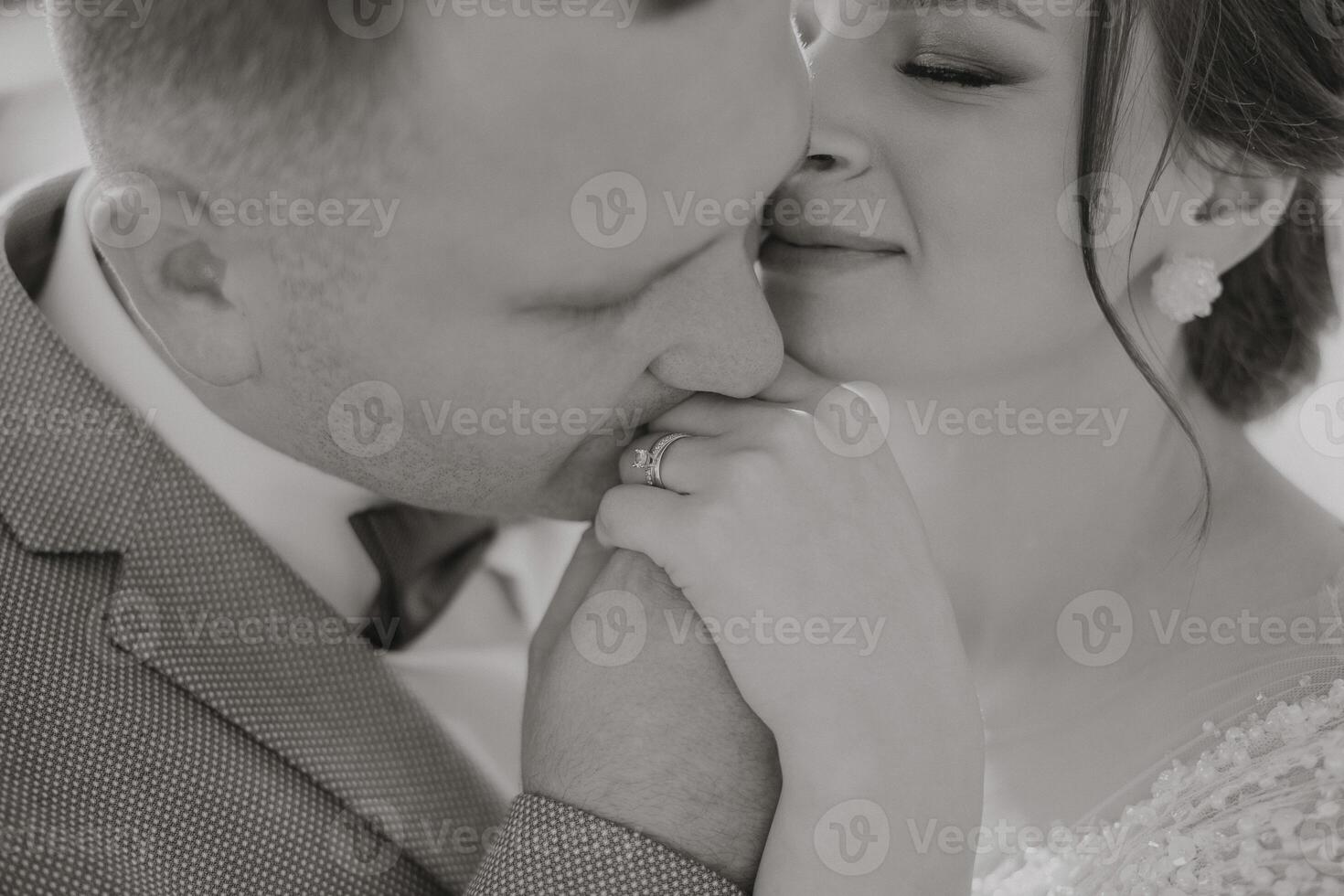 A man and woman are kissing each other's hands. The man is wearing a wedding ring photo