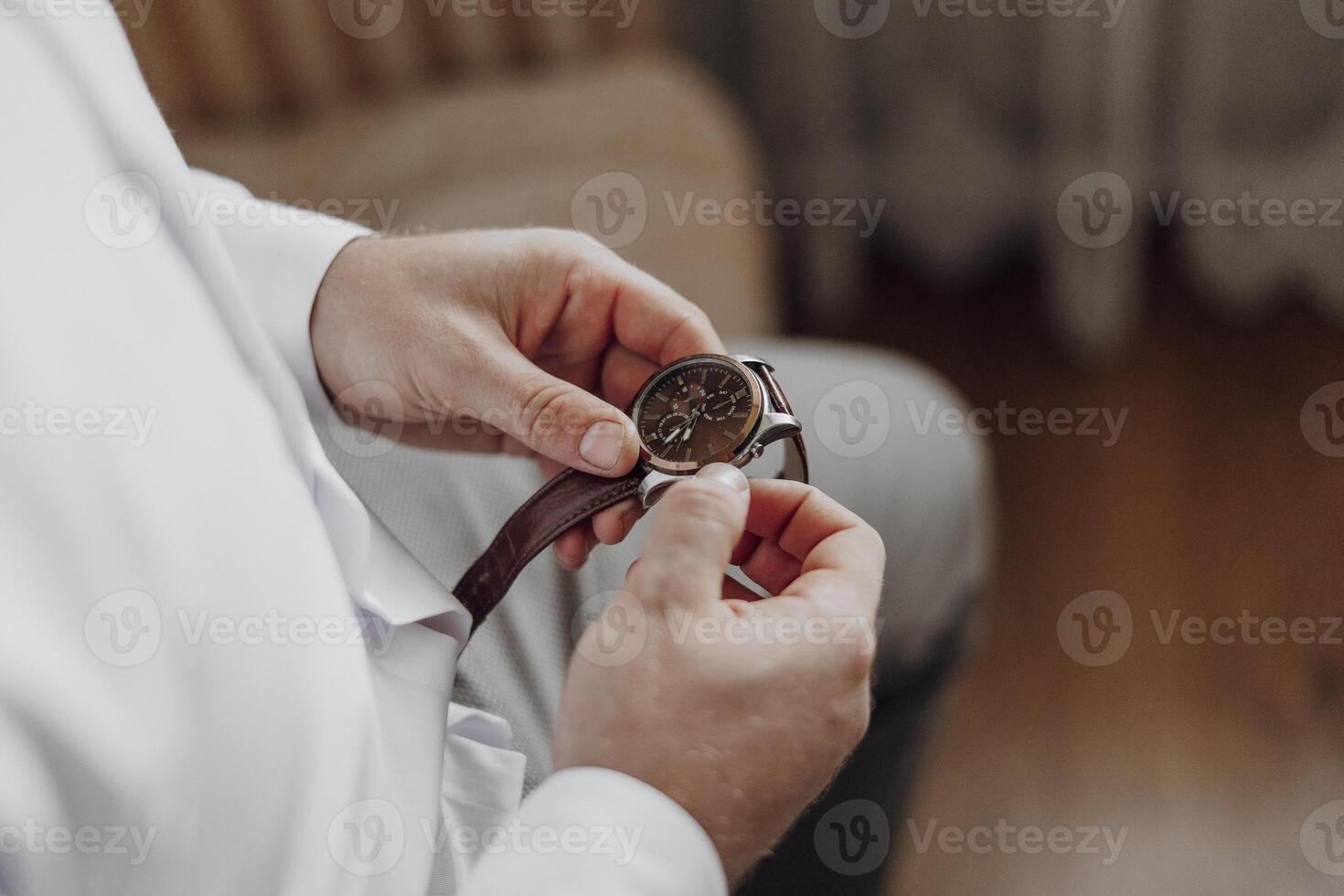 A man is wearing a watch and adjusting it. The watch is brown and has a silver band photo