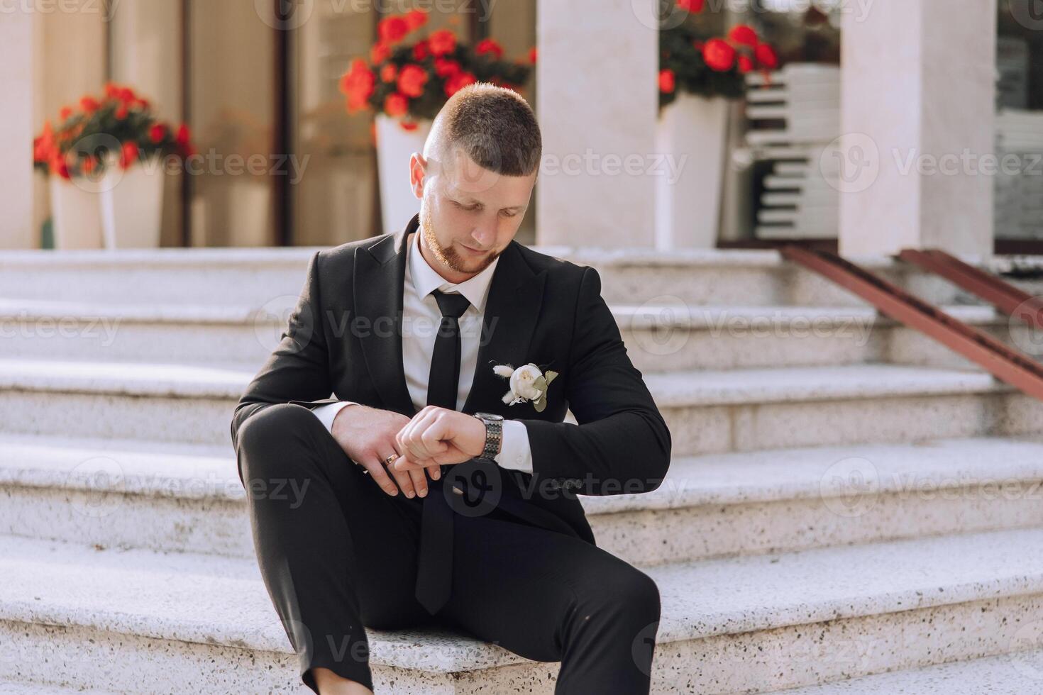 A man in a suit and tie is sitting on a set of stairs photo
