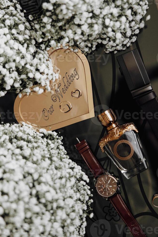 A heart-shaped card with the words written on it sits on a table with a bottle of perfume and a watch photo