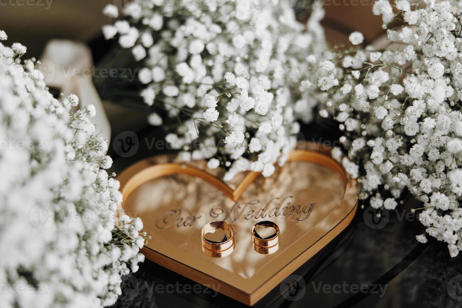 A heart-shaped box with two rings inside and a watch on top. Concept of love and commitment photo