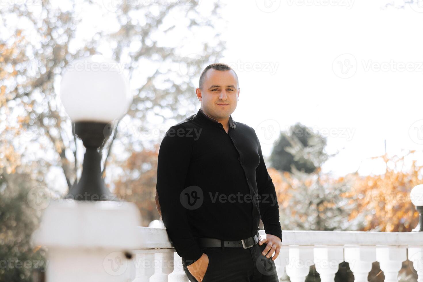 A man in a black shirt stands on a balcony photo