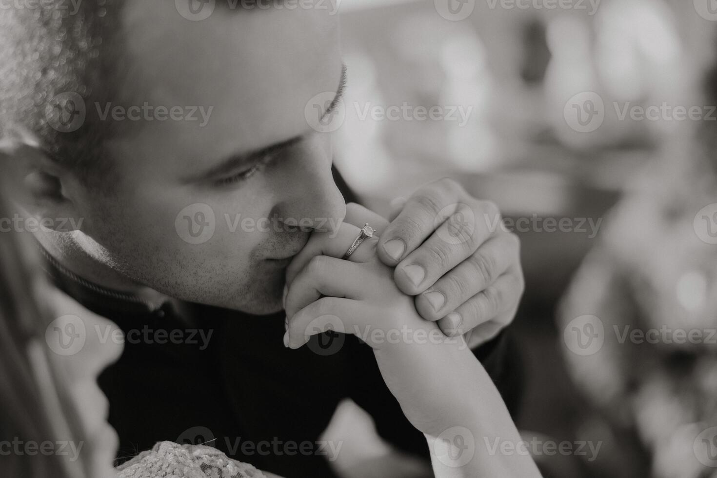 A man kisses a woman's hand, and she is wearing a ring photo