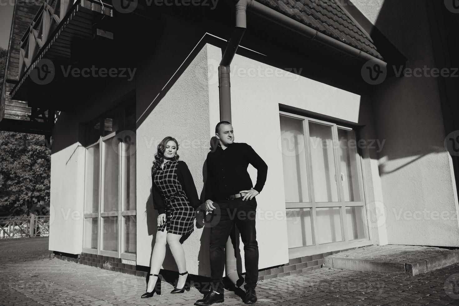 A man and woman stand in front of a building, with the man wearing a black shirt photo