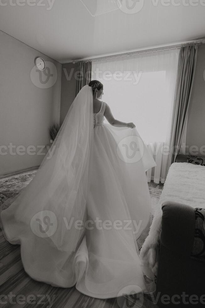 A bride is walking out of a room with a white dress and veil photo