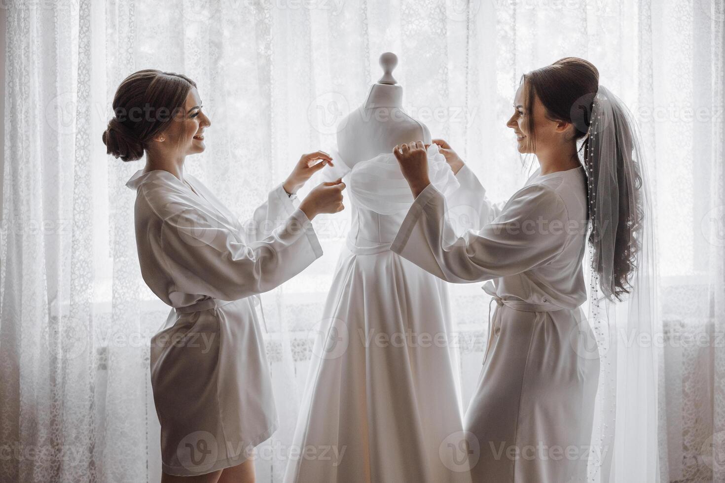 Two women are standing in front of a wedding dress photo