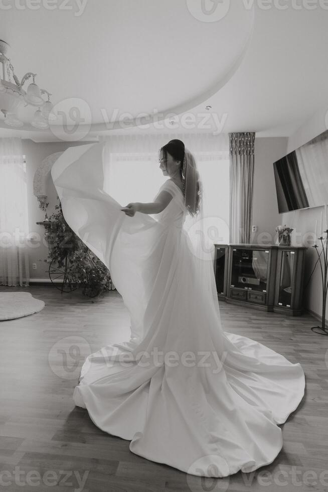 A woman in a white dress is standing in a room with a large mirror photo