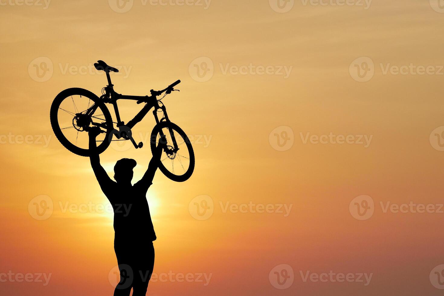 Silhouette of Cyclist Holding Bicycle Against Vibrant Sunset Sky photo
