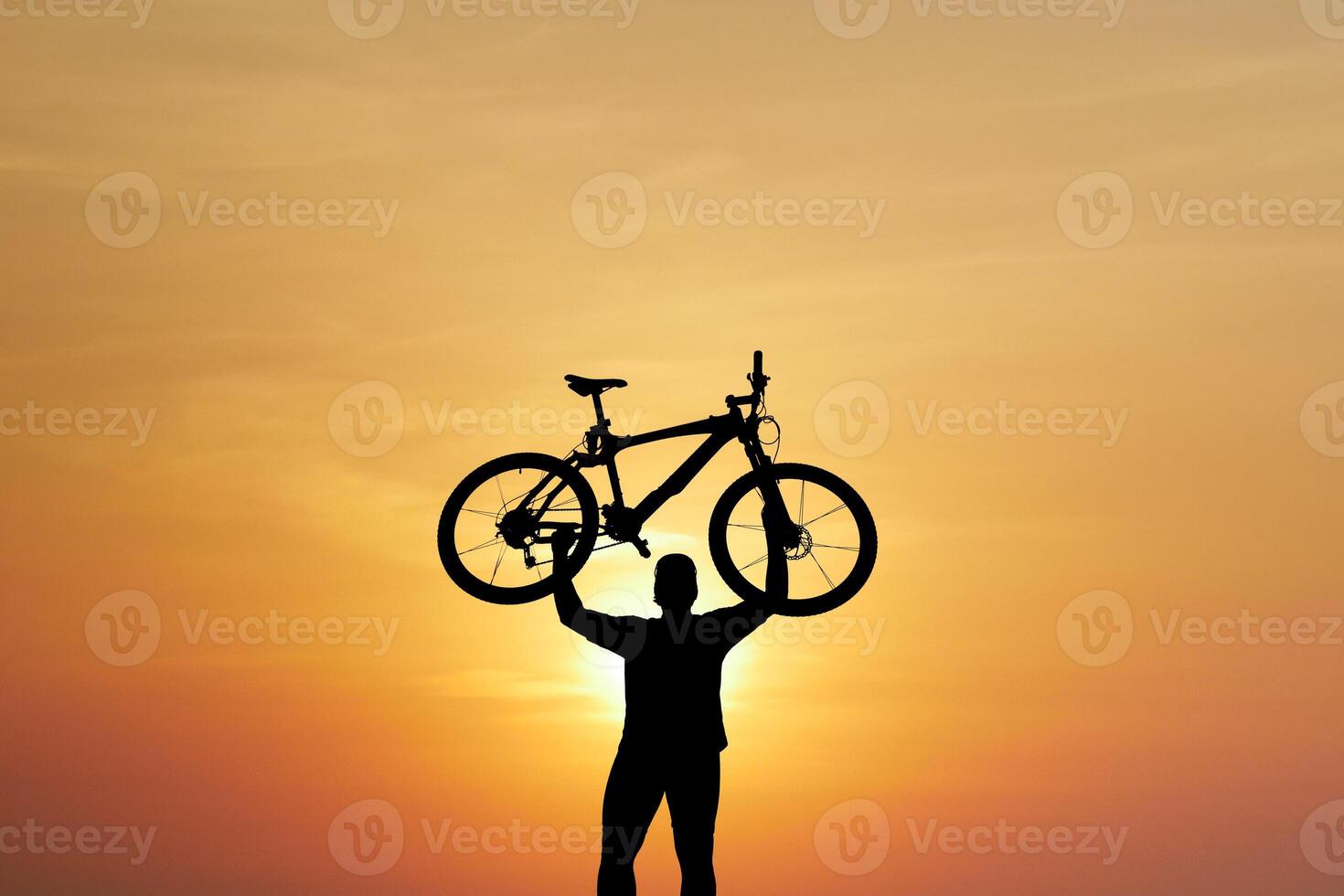 Silhouette of Person Holding Bicycle Against Vibrant Sunset Sky photo