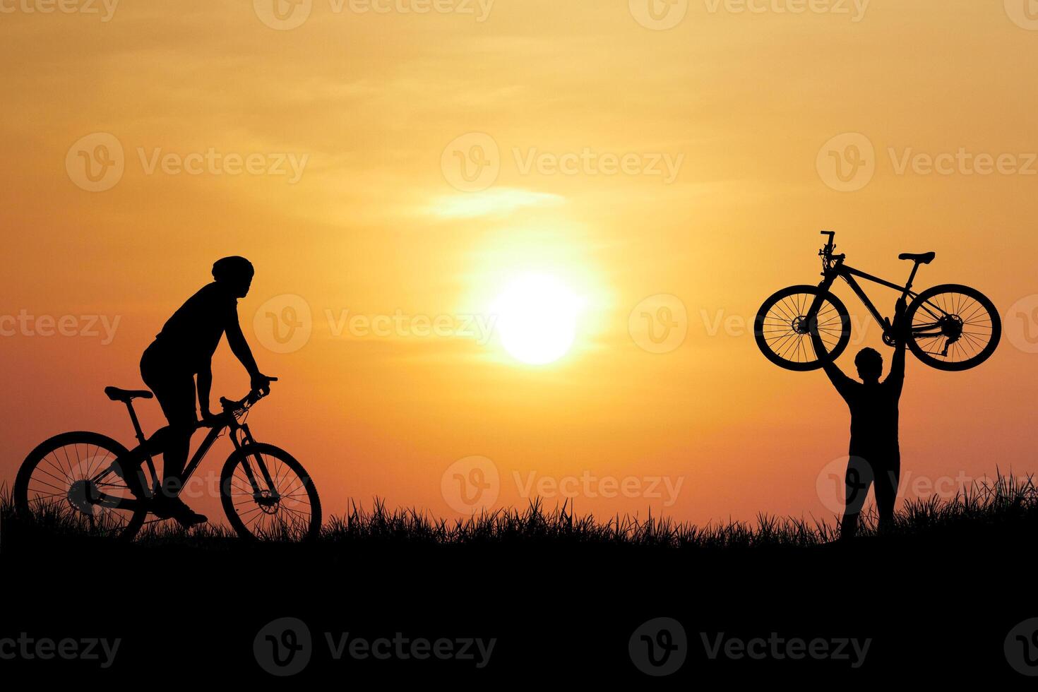 Silhouettes of Cyclists at Sunset with One Holding a Bicycle in the Air Against a Vibrant Orange Sky photo