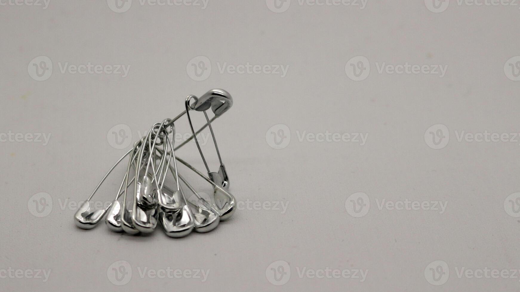 The safety pin is made of metal and silver in color. photo