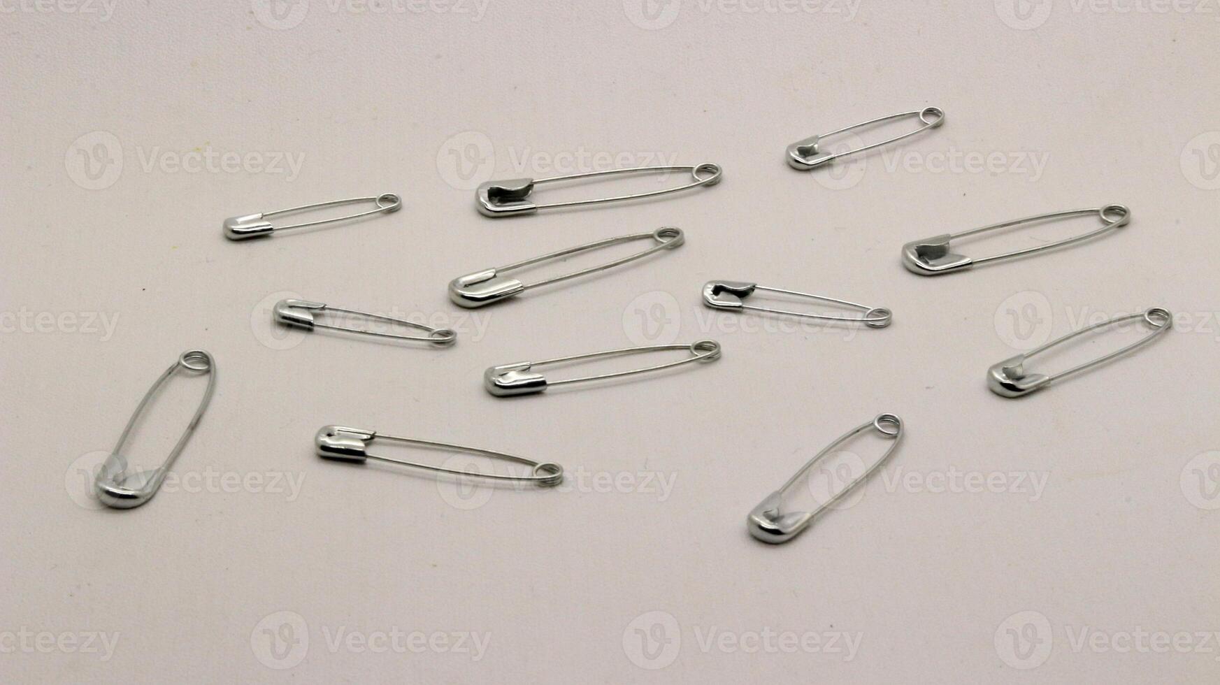 The safety pin is made of metal and silver in color. photo