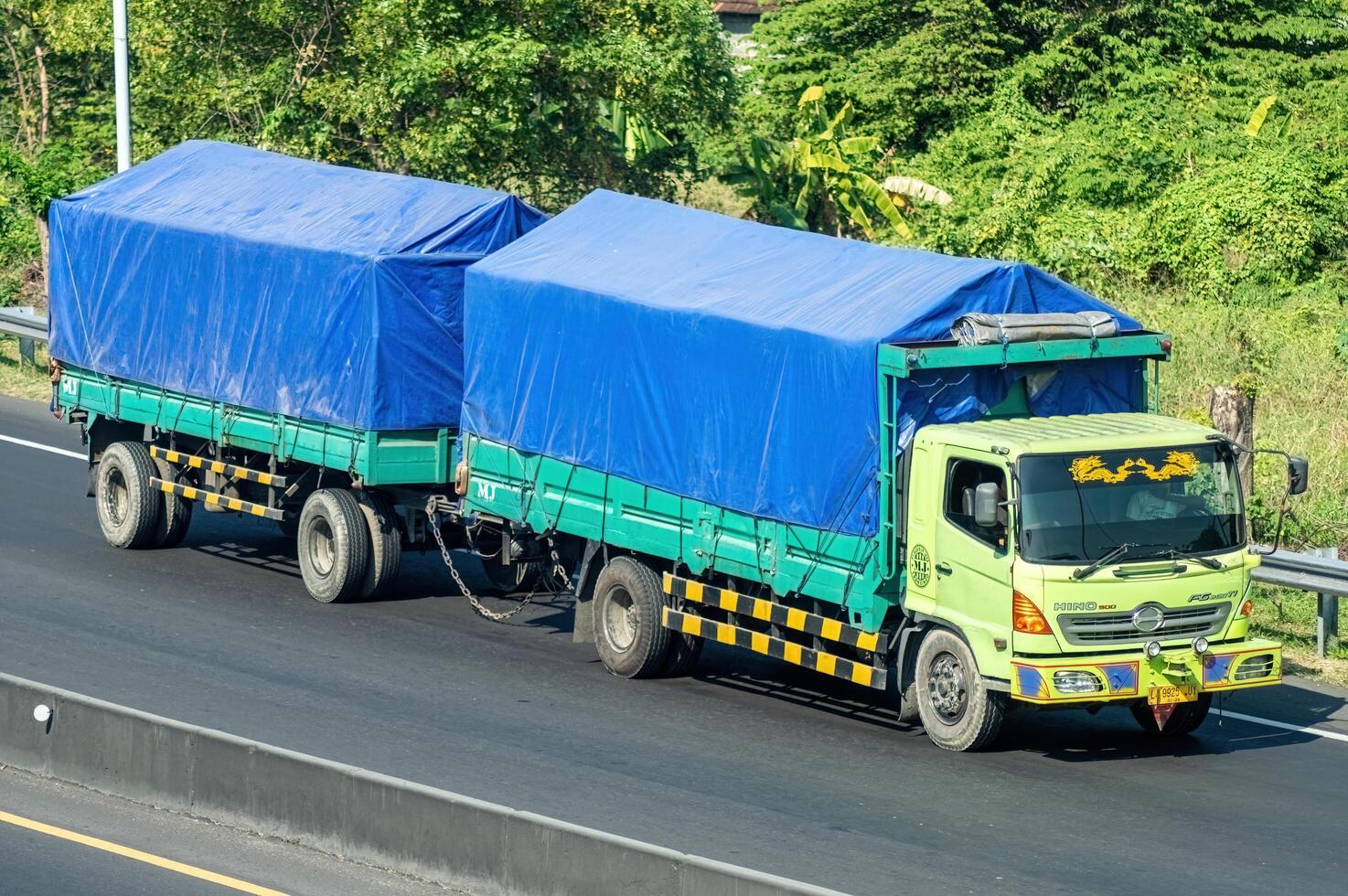 a trailer truck or articulated lorry passing on the Surabaya Gresik toll road carrying a full load of logistics, Indonesia, 16 July 2024. photo