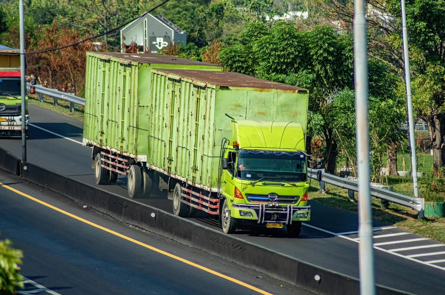 a trailer truck or articulated lorry passing on the Surabaya Gresik toll road carrying a full load of logistics, Indonesia, 16 July 2024. photo