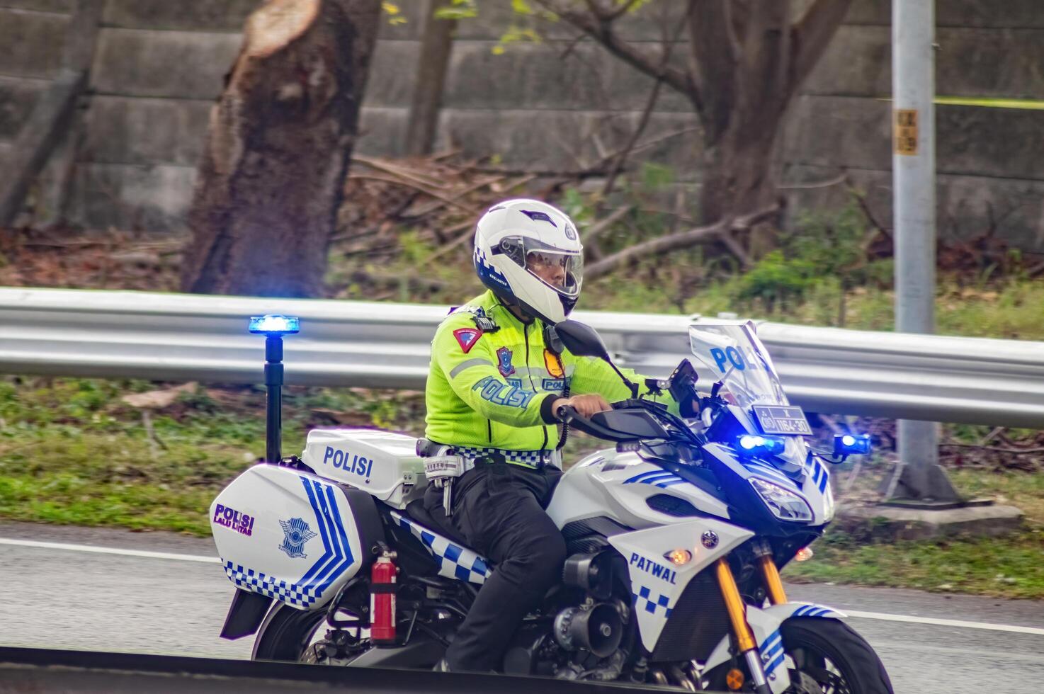 a traffic policeman riding a police sports motorbike on the Surabaya toll road is carrying out an escort and turning on strobe lights along the road, Indonesia, 16 July 2024. photo