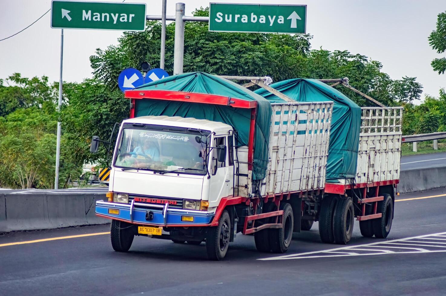 a trailer truck or articulated lorry passing on the Surabaya Gresik toll road carrying a full load of logistics, Indonesia, 16 July 2024. photo