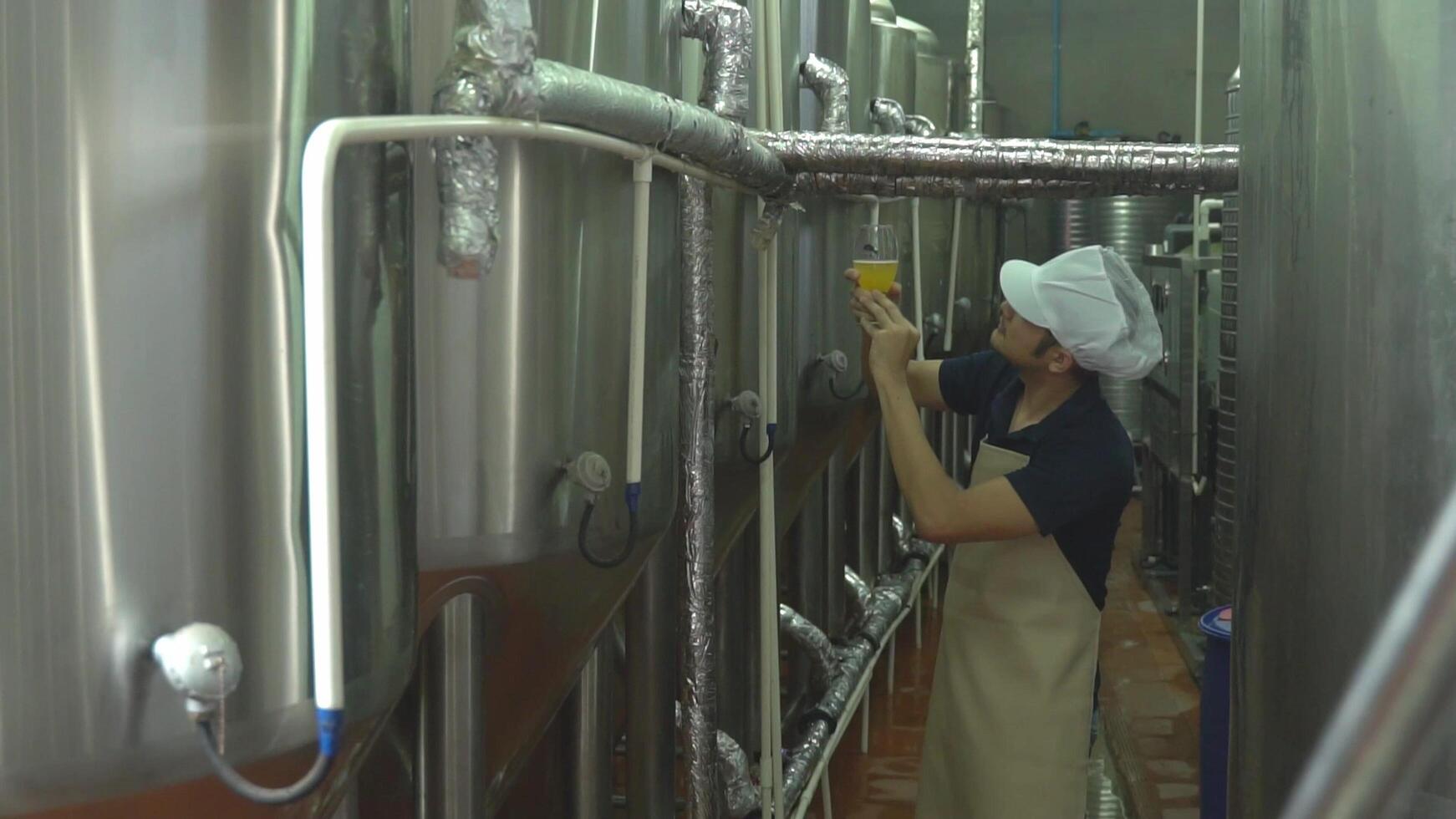 Asian male owner is inspecting the brewery's quality over a glass of craft beer. Ideas for making craft beer photo