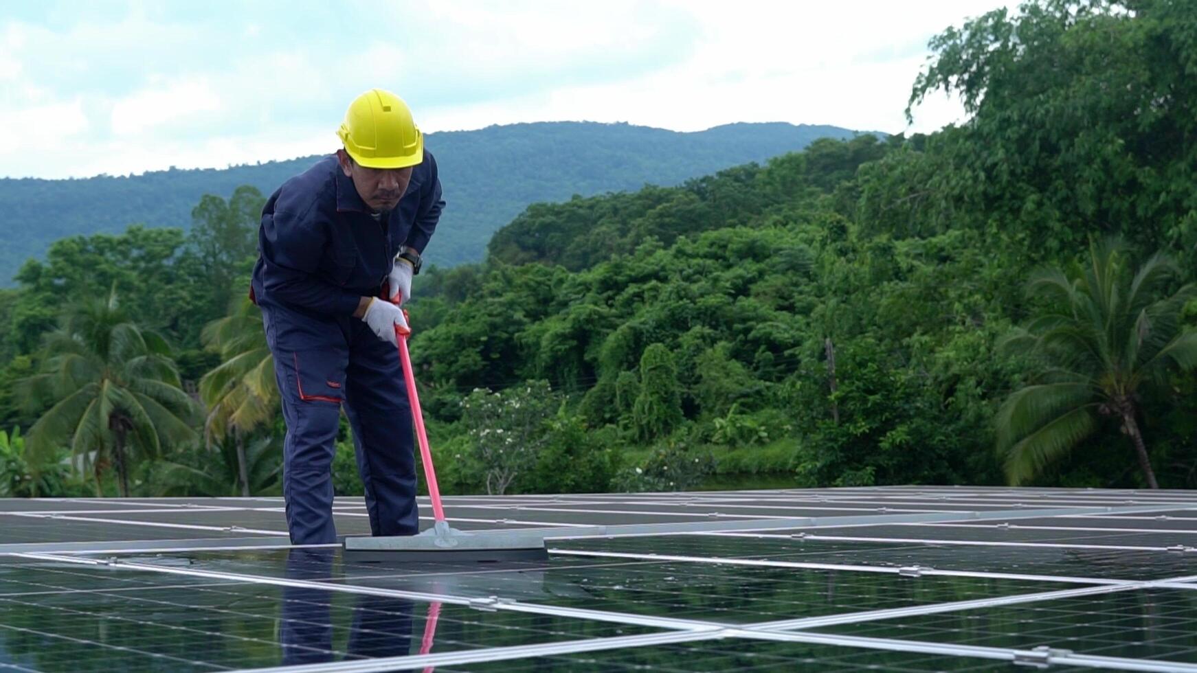 Asian technician Use a mop and water to clean the solar panels dirty with dust to improve the efficiency of solar energy storage. photo