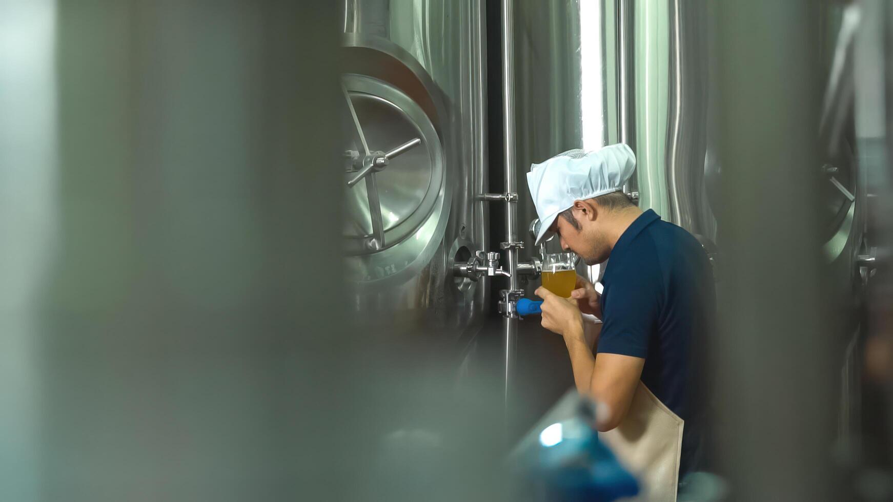 A young Asian worker checks the quality of a brewery by tasting a glass of craft beer. photo