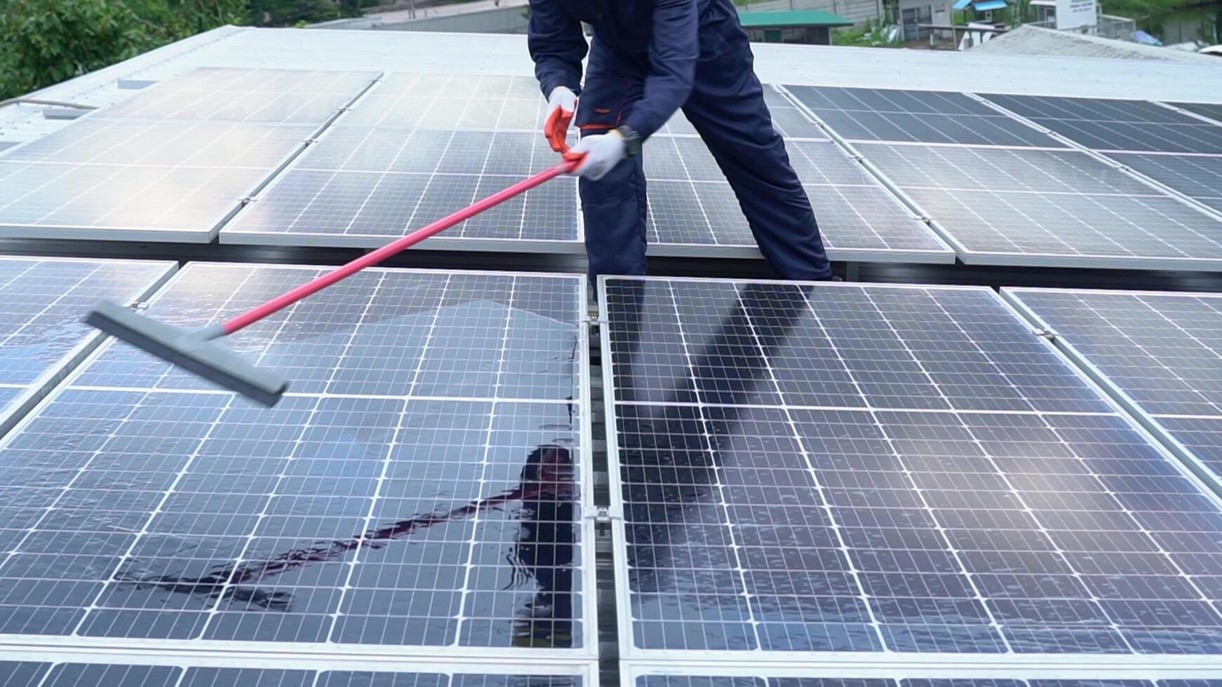 Close up hand Asian technician Use a mop and water to clean the solar panels dirty with dust to improve the efficiency of solar energy storage. photo