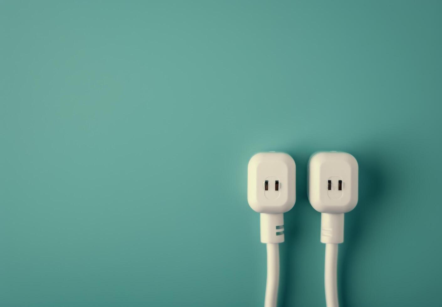 Two White Electrical Plugs on Teal Background photo