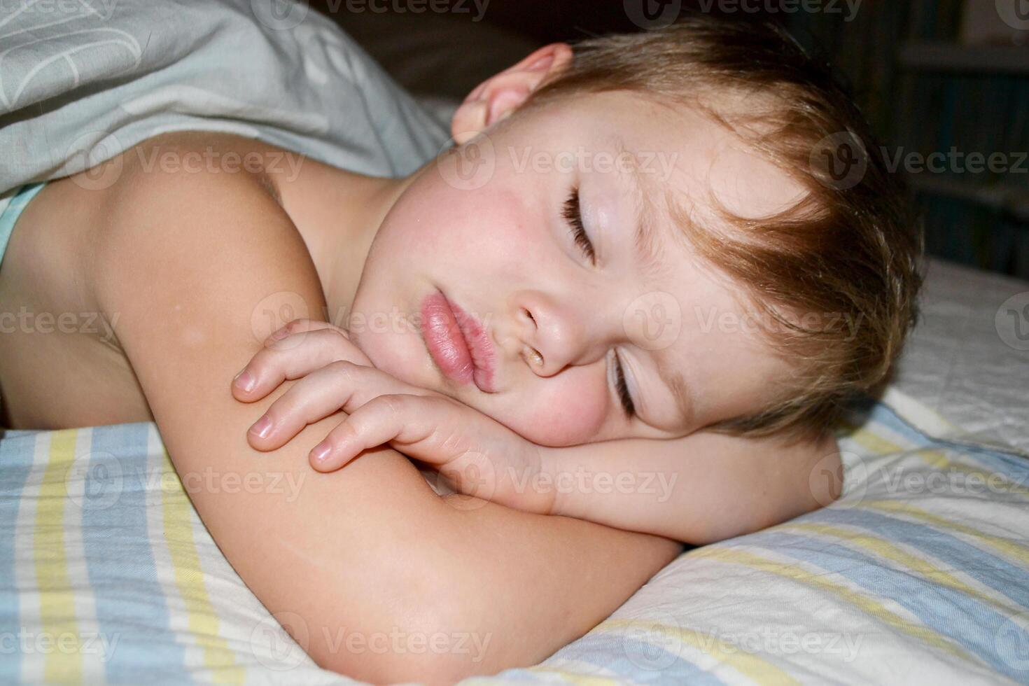 Five years old child sleeping in bed on pillow with a teddy giraffe. photo