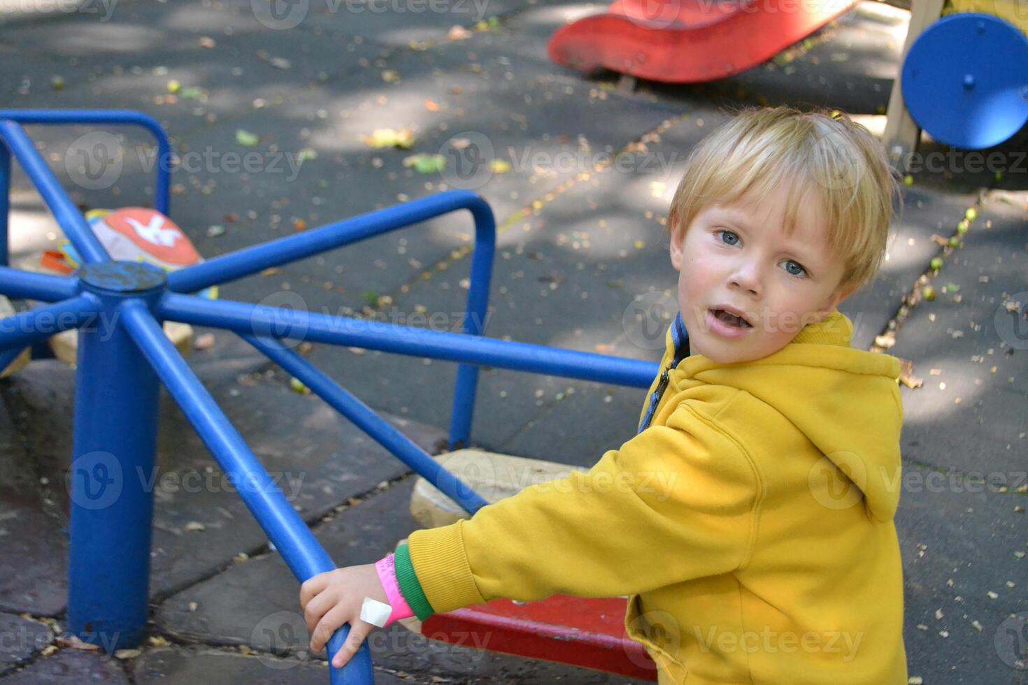 Blond haired boy has fun at playground in local park photo