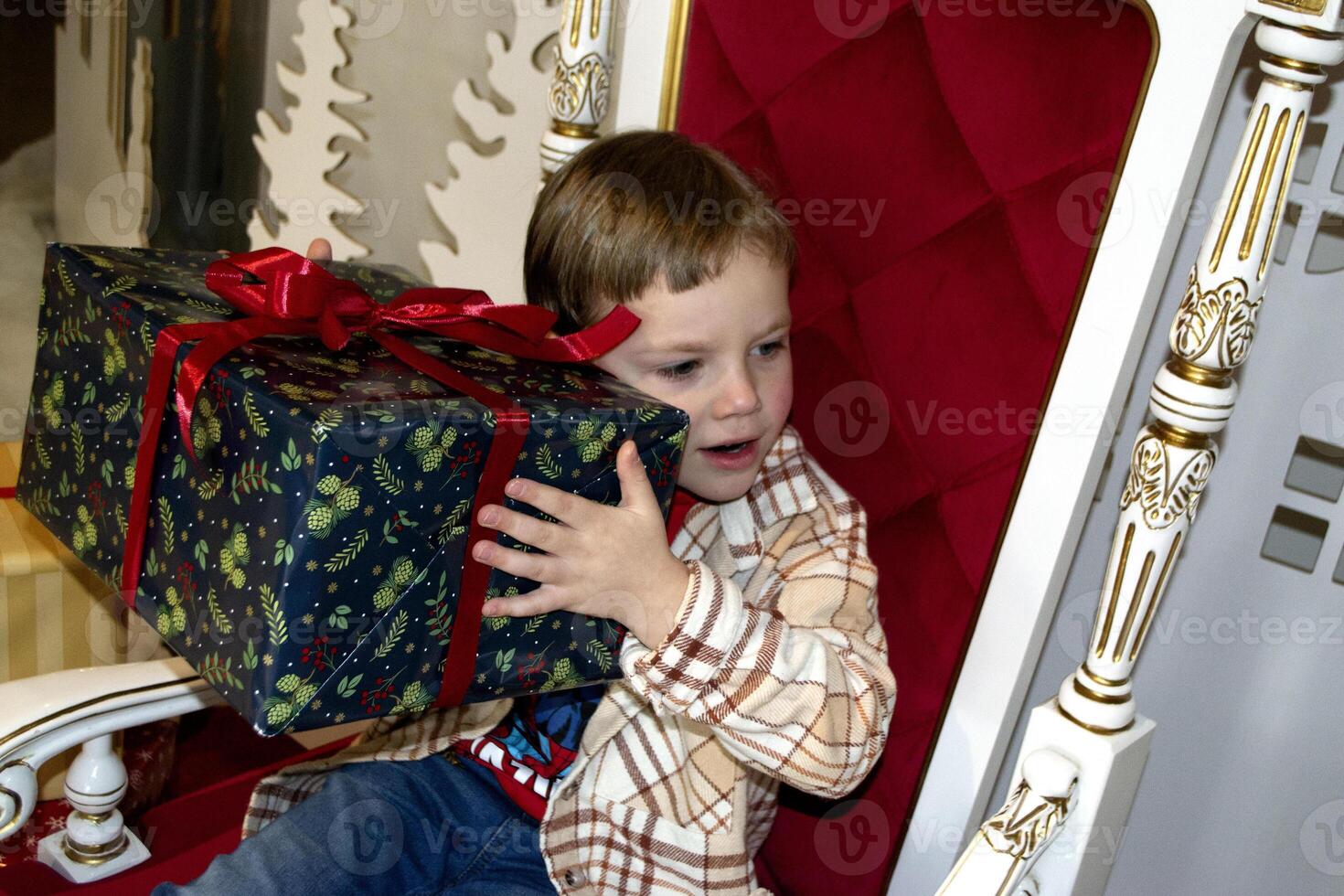 Happy little boy in Santa's hat sitting in a room decorated for Christmas. photo