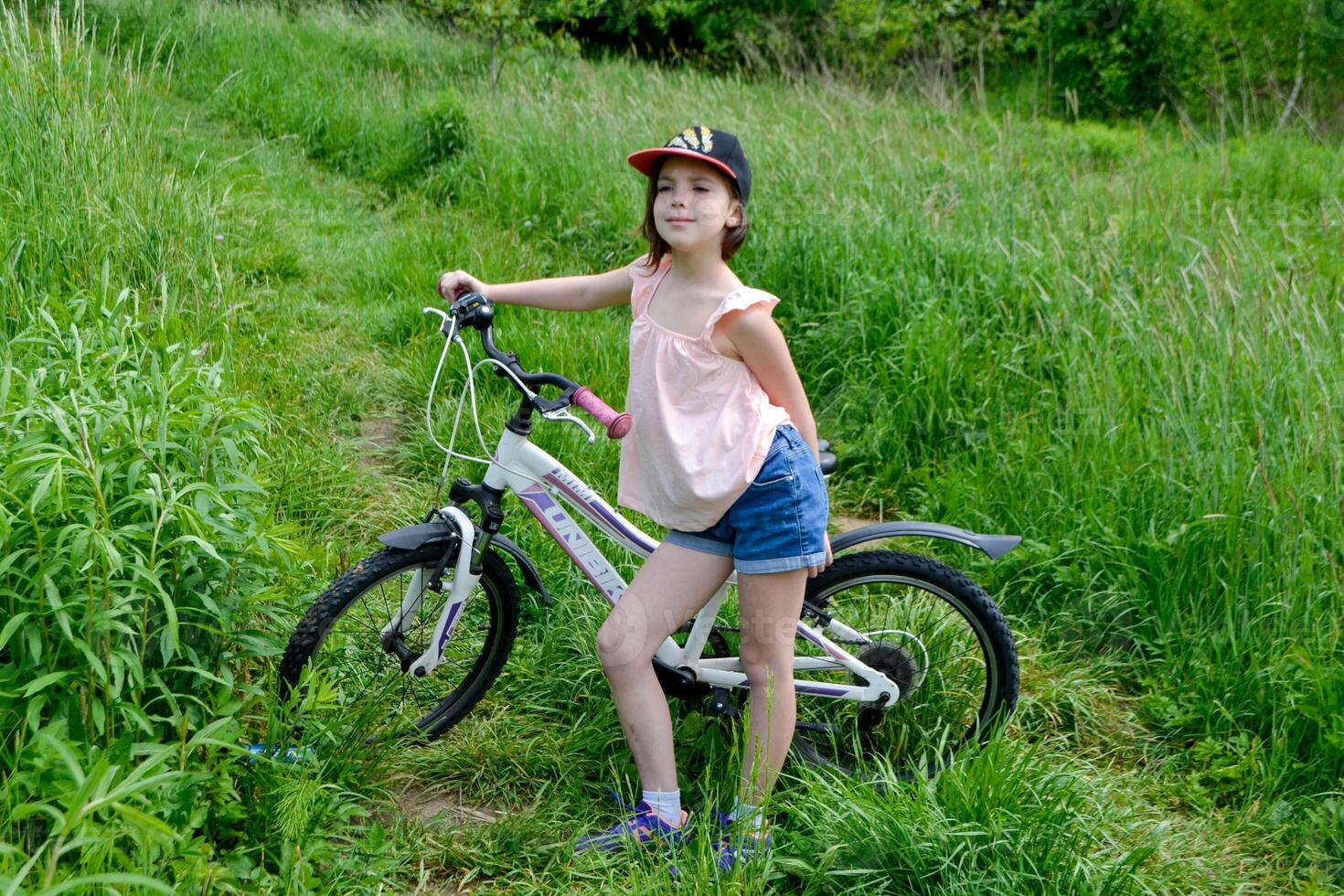 Little cute girl riding a bike with basket full of flowers. photo