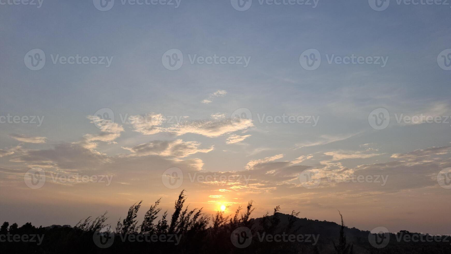 The sun sets behind the hills painting the sky in shades of pink and orange photo