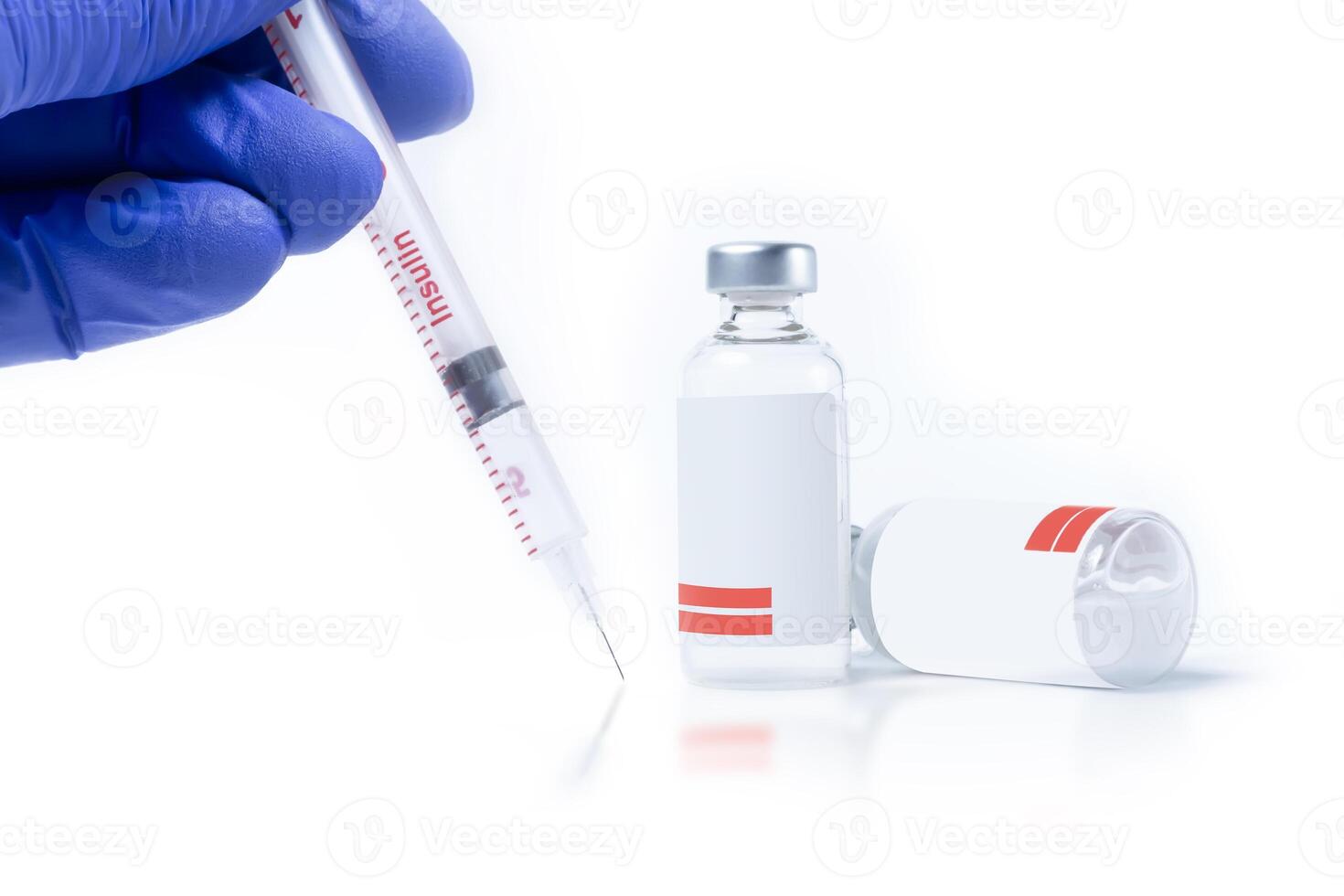 Doctor in blue gloves holding insulin syringe near two vials on white background. photo